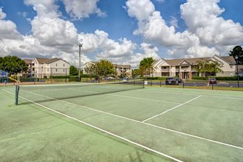 Tennis court with native trees and building in background.